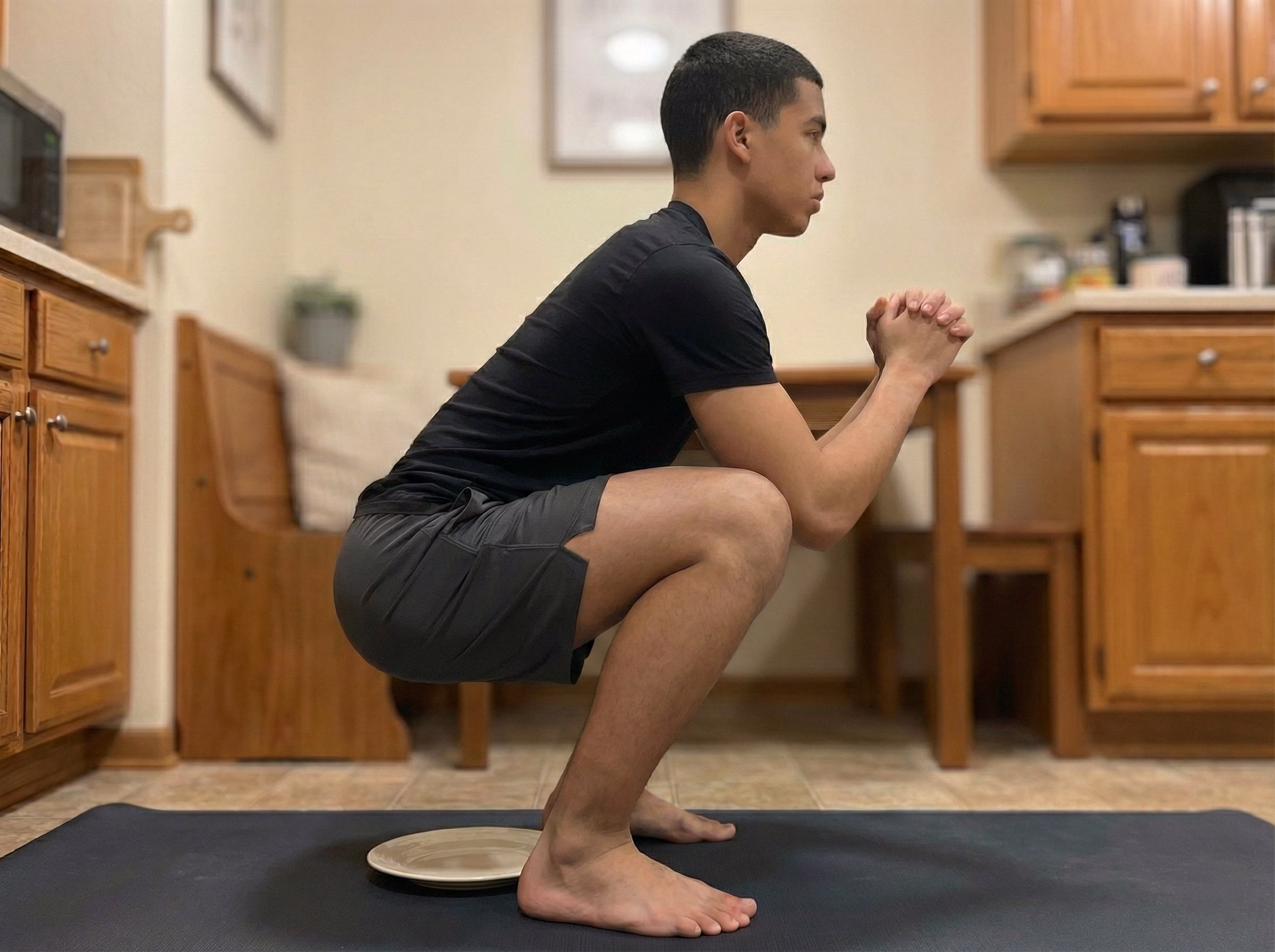 Deep squat hold with heels elevated on small support