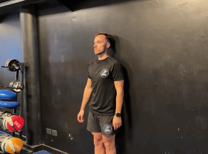 Person performing a wall chin tuck exercise